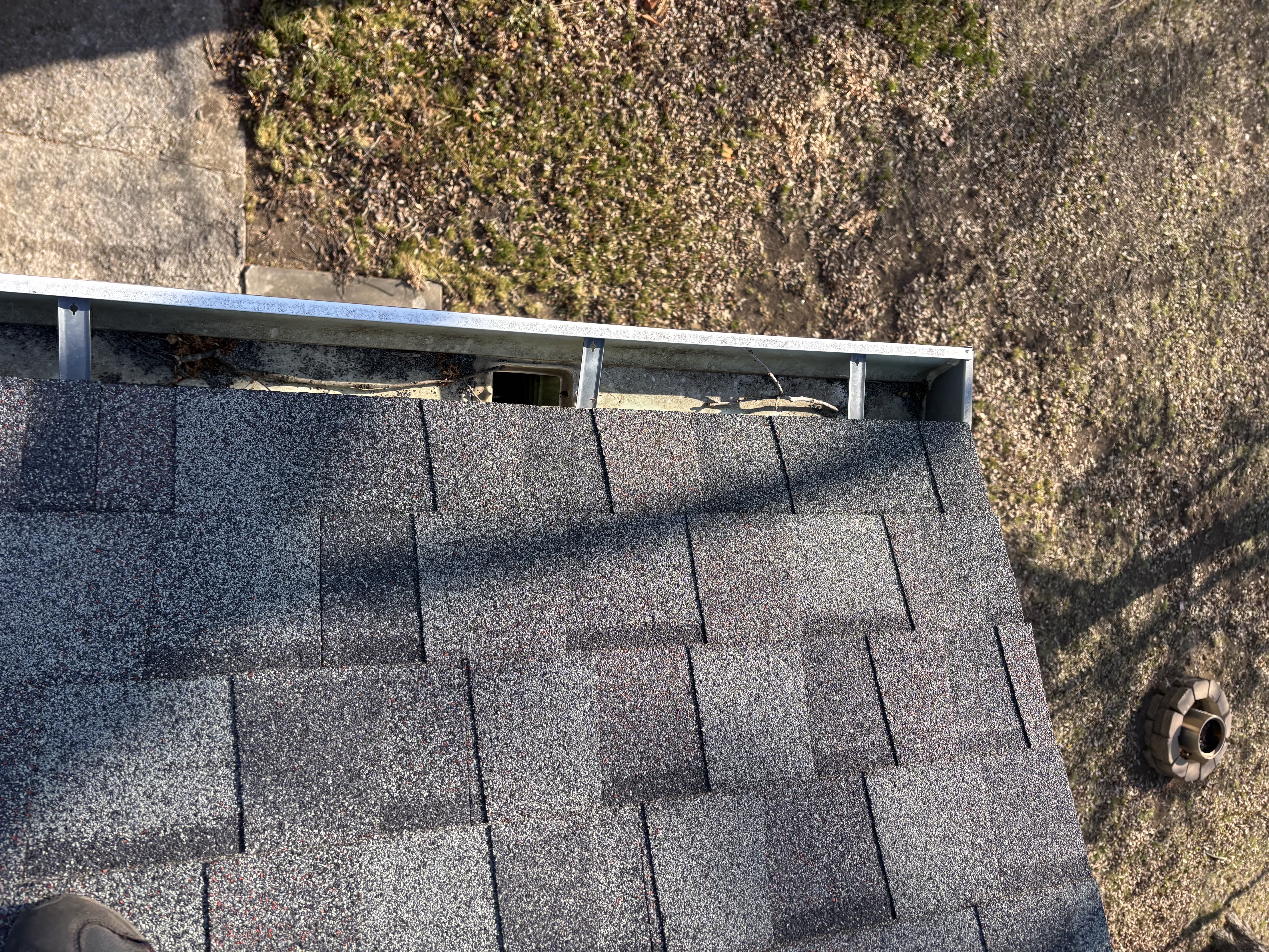Gutter run with visible material near a downspout opening before service