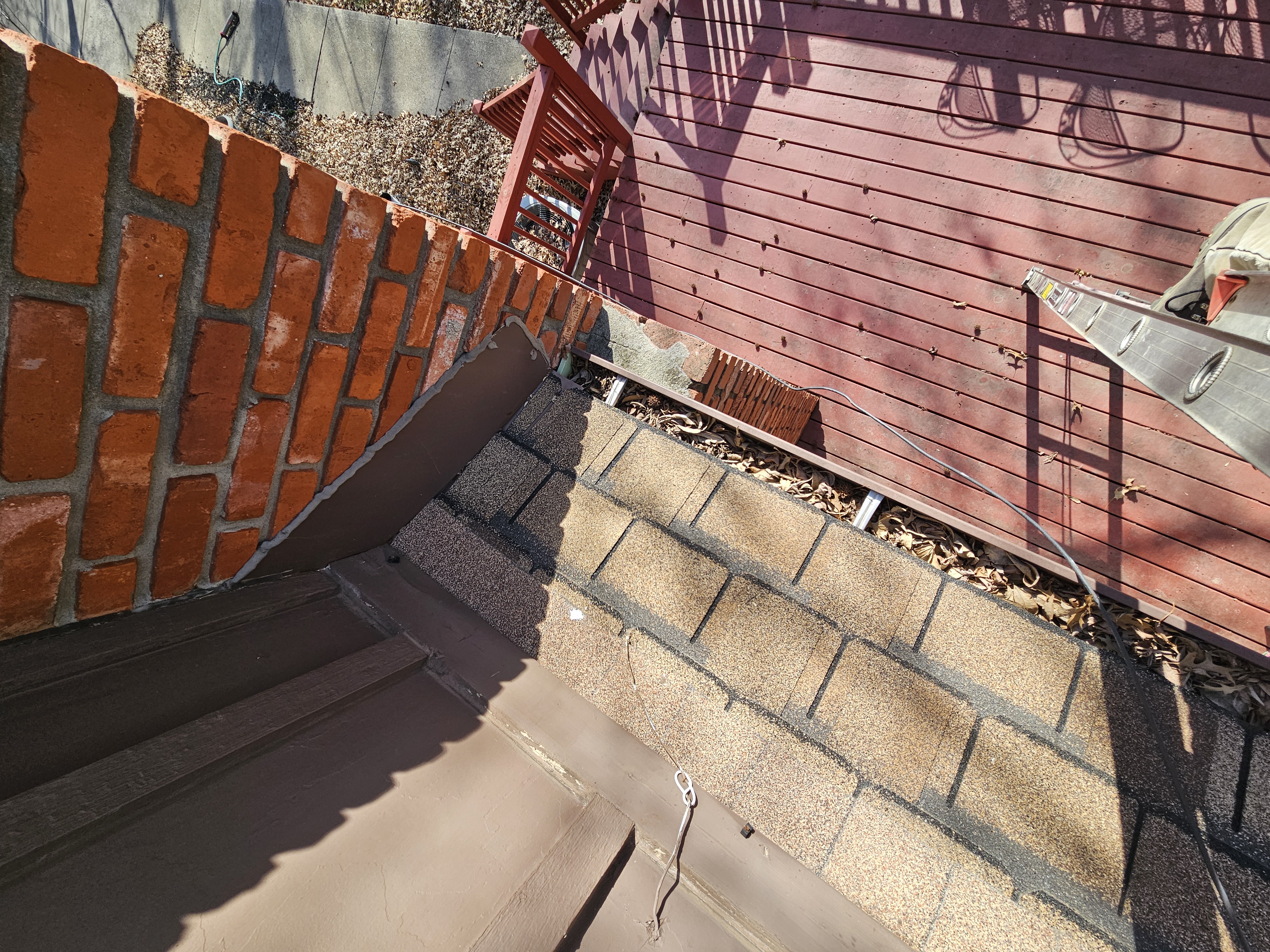 Leaves and organic debris inside a gutter near the deck and chimney before service