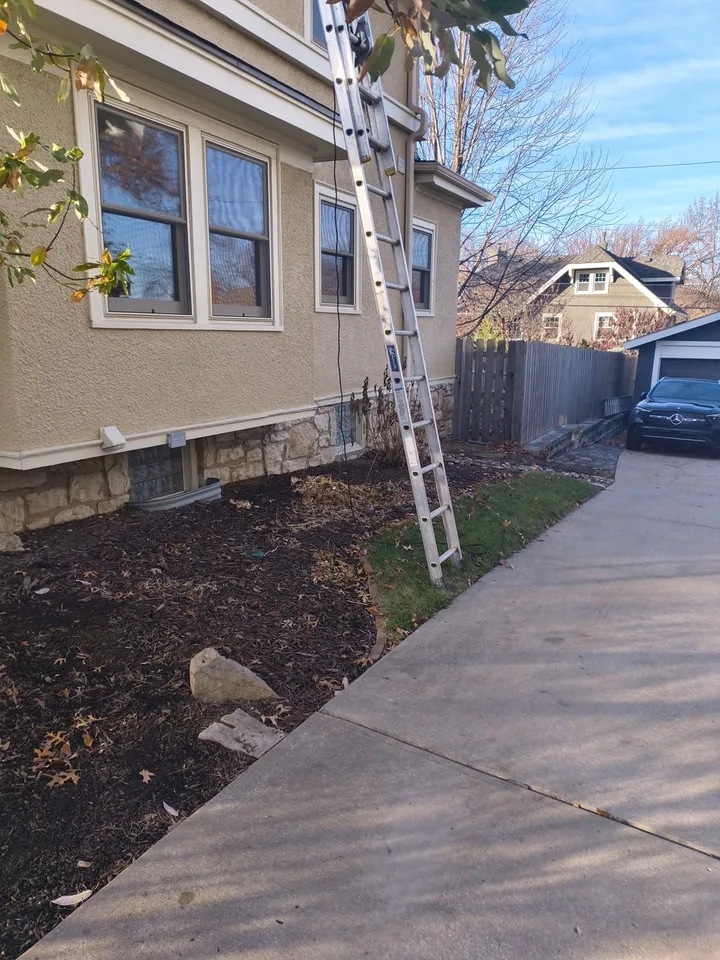 Ladder set at the upper gutter of a two-story Brookside-area home
